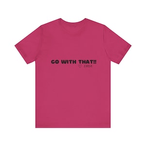May include: A magenta t-shirt with the phrase "GO WITH THAT!!" in black, along with a heart symbol and the word "EMDR" in a handwritten style. The shirt is a solid color and has short sleeves.