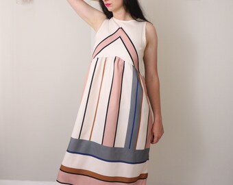 May include: A sleeveless maxi dress with a white background and pink, brown, and blue stripes. The dress has a geometric pattern at the top and a gathered waist.