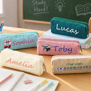 May include: A collection of corduroy pencil cases in various colors, including teal, pink, beige, and green. Each case is personalized with a name, such as "Sophia," "Amelia," "Lucas," and "Toby." One case features a school logo.