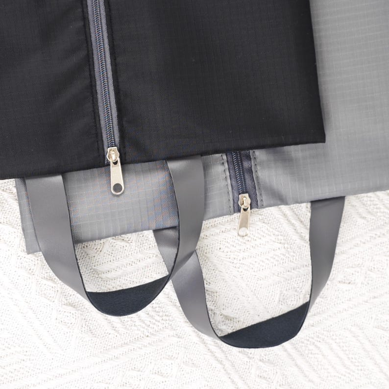 May include: Two gray and black zippered travel bags with black handles. The bags are made of a water-resistant material.