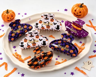 May include: Six hair claw clips featuring Halloween themes, including purple and black checkered patterns with orange pumpkins, white backgrounds with black cats and witch hats, and orange and black plaid, each personalized with the names Sophie or Julie.