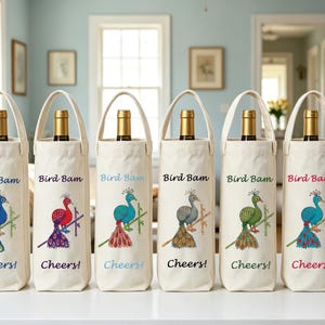 Pode incluir: Seis sacos de lona em tom off-white para garrafas de vinho com alças, cada um com uma ilustração de um pavão colorido pousado num ramo. O texto "Bird Bam" está impresso acima do pavão e "Cheers!" abaixo com tinta da mesma cor.
