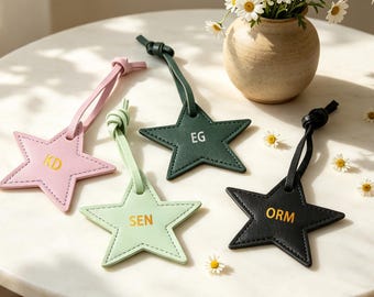 May include: Four star-shaped leather tags with matching leather loops. The pink tag features gold KD lettering, the light green tag has gold SEN lettering, the dark green tag has white EG lettering, and the black tag has gold ORM lettering.