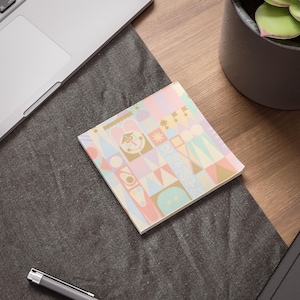 May include: A pastel-colored notepad with a geometric pattern featuring a whimsical castle design. The notepad is perfect for jotting down notes, ideas, or reminders.