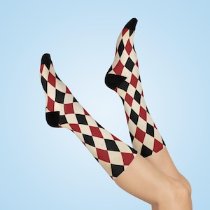 Puede incluir: Un par de calcetines hasta la rodilla con un patrón de rombos rojo, negro y blanco.