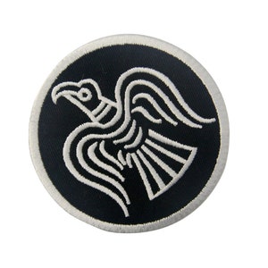 May include: A black and white embroidered patch featuring a stylized bird design. The bird is in a circular shape with a white outline.
