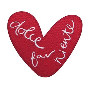 Puede incluir: Parche rojo en forma de corazón con bordado blanco que dice "dolce far niente".