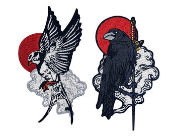 May include: Two embroidered patches featuring birds and Japanese-inspired designs. One patch depicts a bird with outstretched wings against a red sun. The other shows a raven with a sword, set against a red sun and cloud motif.