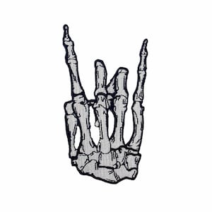 以下が含まれることがあります： ロックンロールのハンドジェスチャーをするスケルトンの手の黒と白の刺繍パッチ