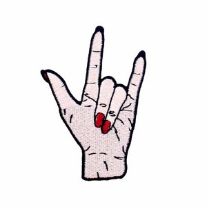 May include: An embroidered iron-on patch of a hand giving the rock and roll hand gesture. The hand is white with black outlines and red nail polish.