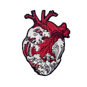 Puede incluir: Corazón anatómico rojo bordado con olas blancas, un diseño estilizado para un parche o plancha.