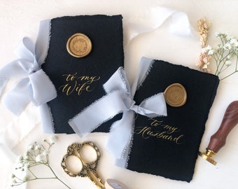 Boeken met kalligrafie-huwelijksgeloften: zwart handgeschept papier met stoffig blauw zijden lint