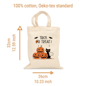 Op de afbeelding: Een witte katoenen draagtas met de tekst "Trick or Treat!" erop gedrukt. De tas heeft een zwarte kat en drie oranje pompoenen met jack-o'-lantern gezichten. De tas is 32 cm hoog en 26 cm breed.