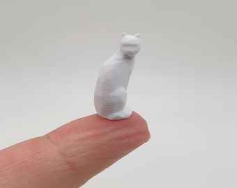 Könnte beinhalten: Eine kleine, weiße, 3D-gedruckte Figur eines sitzenden Katers mit eingezogenen Pfoten.