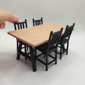 May include: A black wooden dining table set with four chairs. The table has a light brown wood top and black legs. The chairs are also black wood with a simple design.