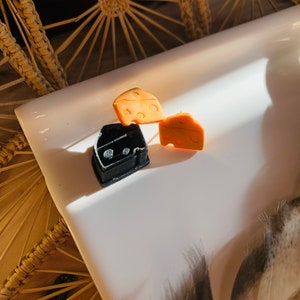 May include: Two pairs of cheese-shaped earrings, one pair is black and the other is orange.
