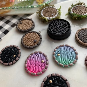 May include: A collection of 10 handmade miniature round doors with various colors and patterns. The doors are made of polymer clay and have a 3D effect. Some doors have a gold accent.