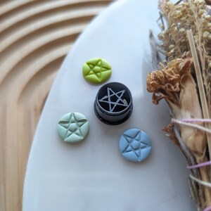 May include: Four small ceramic tiles with five-pointed star designs. One tile is black with a white star, one is light green with a white star, one is light blue with a white star, and one is yellow with a white star.