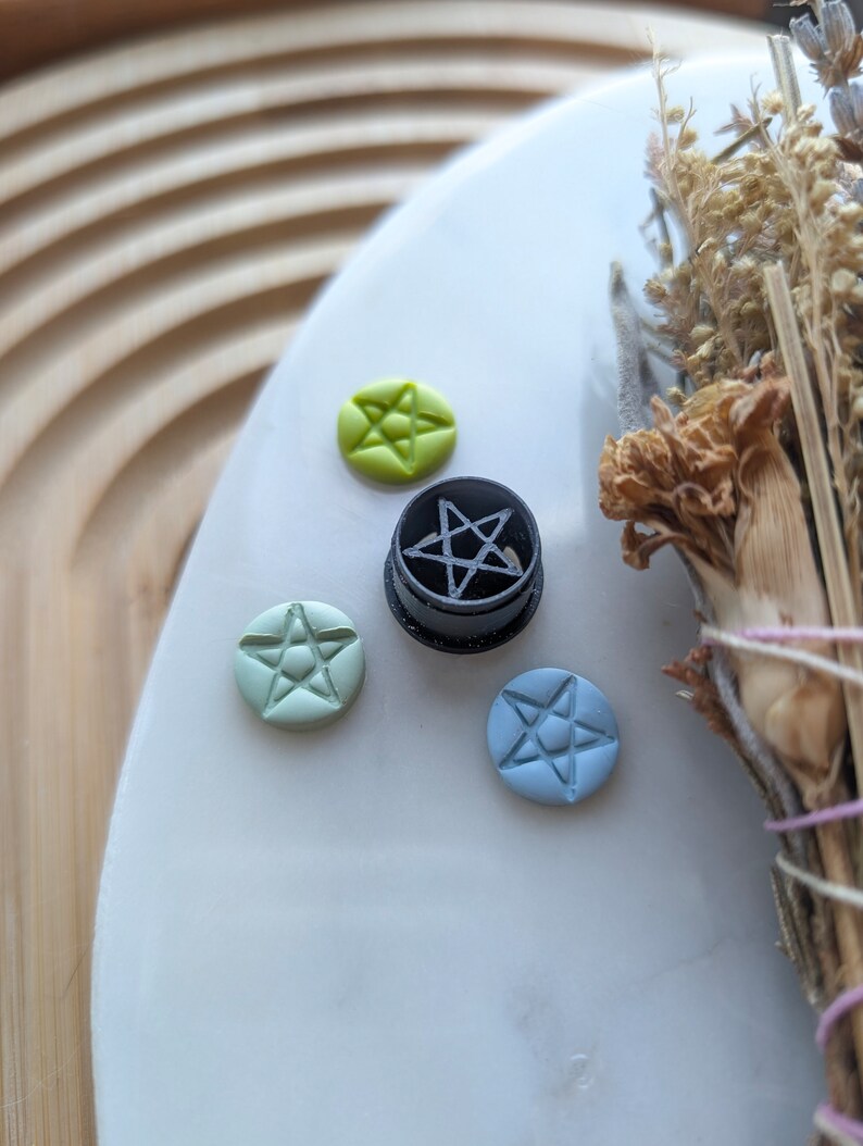 May include: Four small ceramic tiles with five-pointed star designs. One tile is black with a white star, one is light green with a white star, one is light blue with a white star, and one is yellow with a white star.