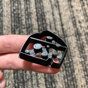 May include: Black plastic cookie cutter shaped like a house with a tree and multiple circles inside.