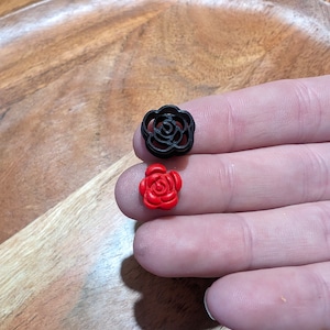 May include: Two small rose-shaped buttons, one black and one red.