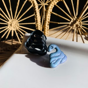 May include: Two small, decorative figurines. One is a black, abstract shape, and the other is a blue, iridescent snake.
