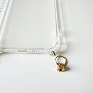 May include: A clear phone case with a gold metal ring and screw attachment.