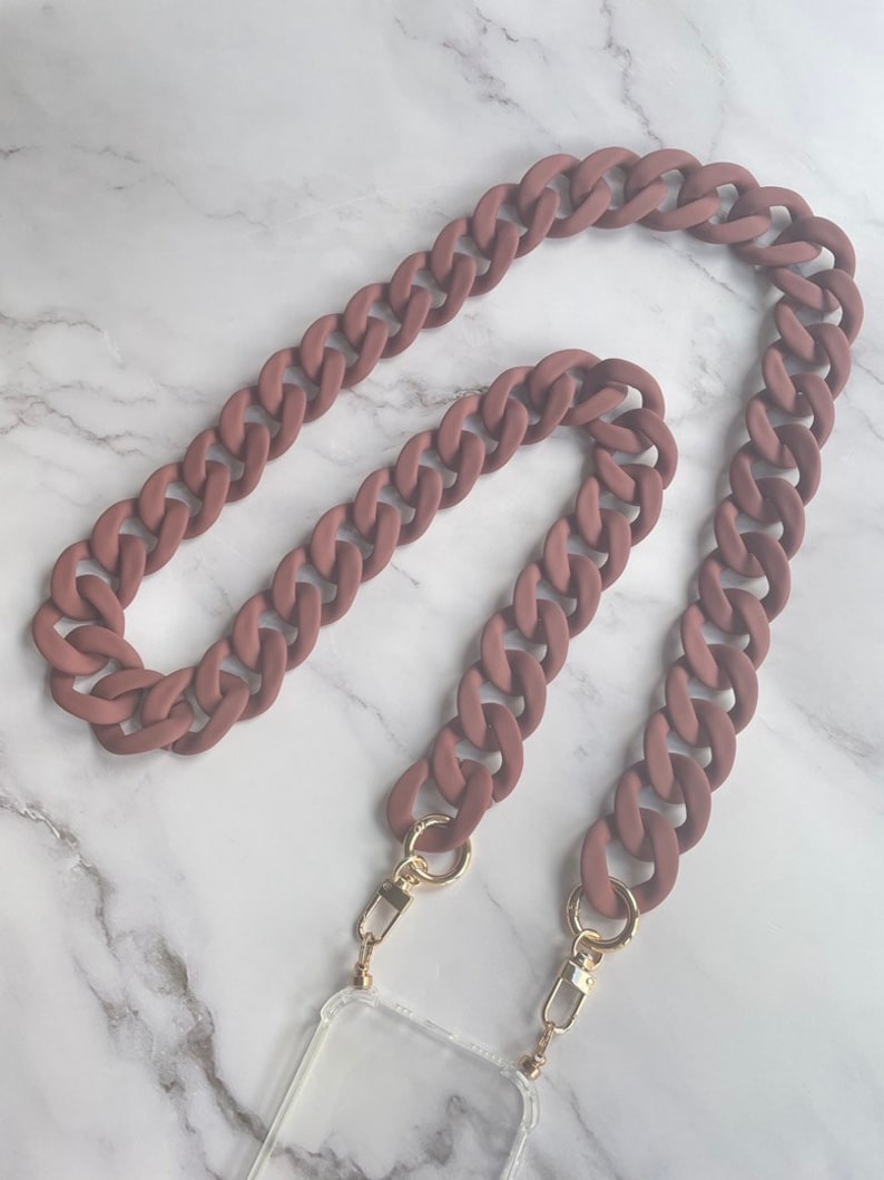 May include: A brown silicone phone chain with gold clasps. The chain is made of thick, chunky links and is designed to be worn around the neck.