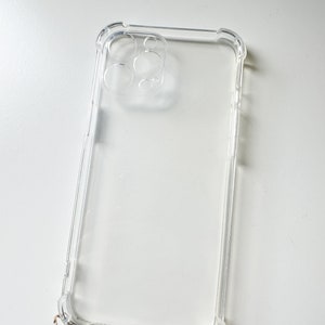 May include: Clear phone case with a raised camera bump and gold accents.