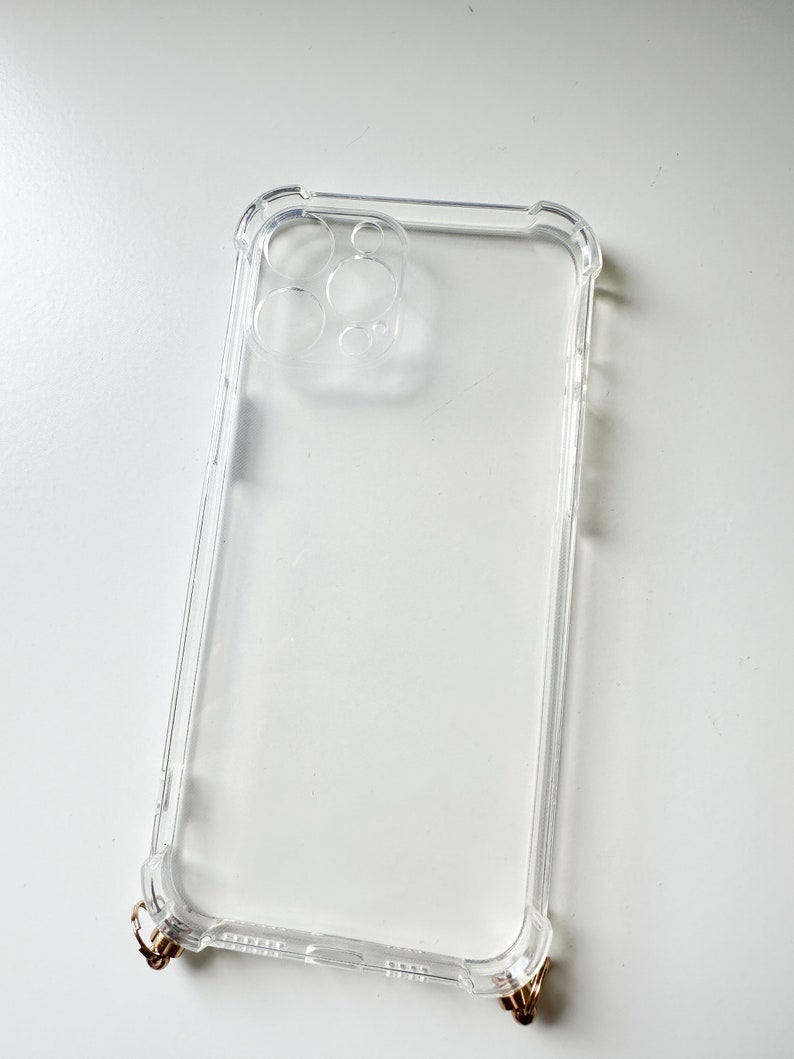 May include: Clear phone case with a raised camera bump and gold accents.