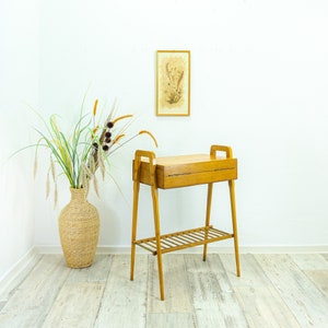 May include: A light wood side table with a drawer and a lower shelf. The table has a simple, mid-century modern design.