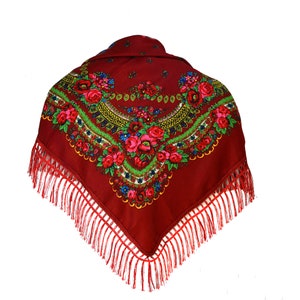 Peut inclure: Un foulard carré rouge avec un motif floral et des franges. Le motif présente des fleurs rouges, vertes, bleues et jaunes.
