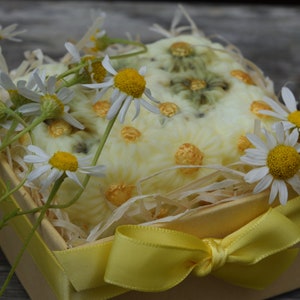 May include: A yellow gift box with a white and yellow floral design, tied with a yellow ribbon and filled with white and yellow flowers.
