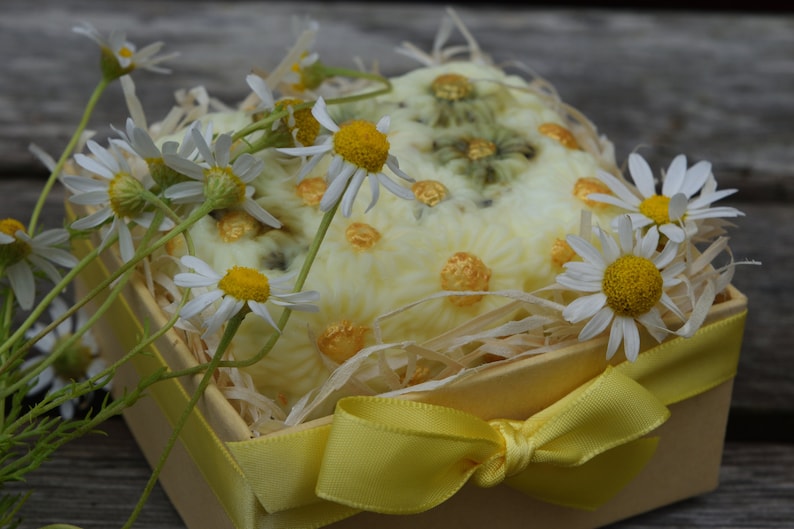 May include: A yellow gift box with a white and yellow floral design, tied with a yellow ribbon and filled with white and yellow flowers.