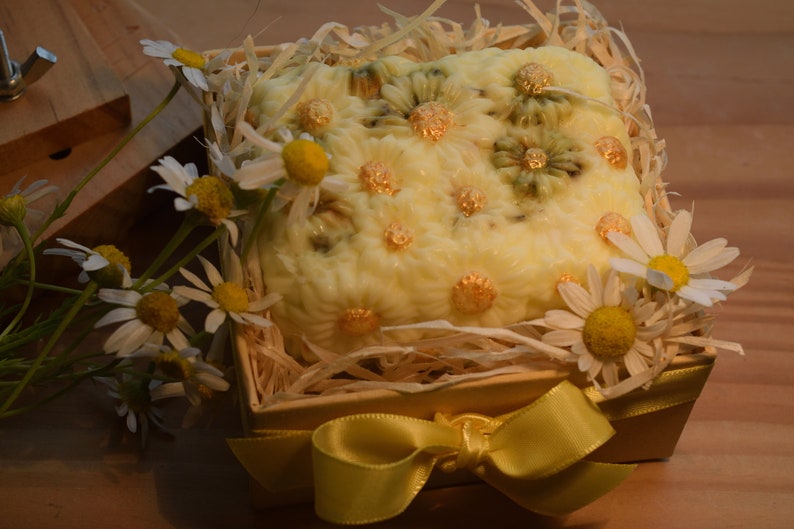 May include: A yellow and white soap bar with a daisy design, in a small wooden box with straw and a yellow ribbon.