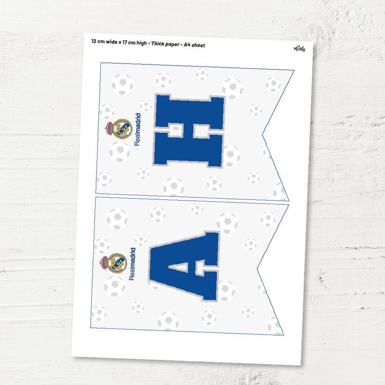 May include: Two printable pennant flags with a white background and a blue letter, "H" and "A", in the centre. The flags are decorated with a white football pattern and a Real Madrid logo. The text "Realmadrid" is written vertically on each flag.