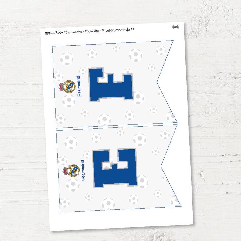 May include: Two printable pennant flags with a white background and a blue letter "E" in the centre. The flags are decorated with a white football pattern and a Real Madrid logo. The text "BANDER&Iacute;N - 12 cm ancho x 17 cm alto - Papel grueso - Hoja A4" is printed at the top of the image.
