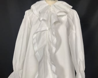 May include: A white long-sleeved blouse with a large ruffled collar and cuffs. The blouse is made of a lightweight fabric and has a relaxed fit.