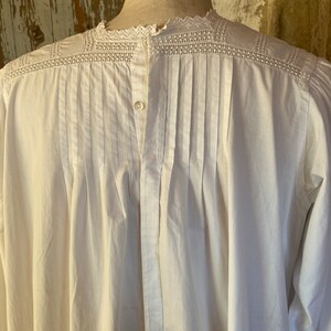 Op de afbeelding: Wit katoenen shirt met een kanten kraag en een knoopsluiting aan de voorkant. Het shirt heeft een geplooide rug en lange mouwen.