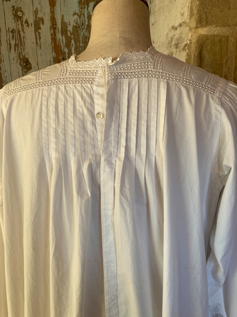 Op de afbeelding: Wit katoenen shirt met een kanten kraag en een knoopsluiting aan de voorkant. Het shirt heeft een geplooide rug en lange mouwen.