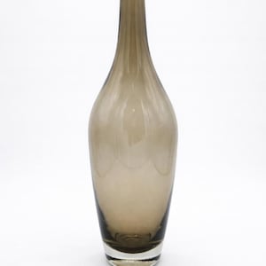 May include: A tall, elegant brown glass vase with a slender neck and a wide, rounded body. The vase has a smooth, glossy finish and a slightly flared base. The overall height is approximately 12 inches.