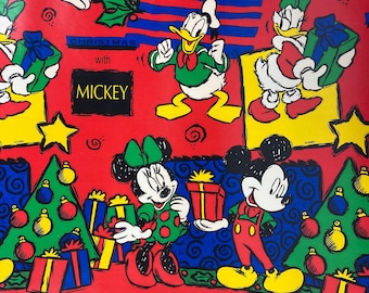 Puede incluir: Papel de regalo rojo con Mickey Mouse, Minnie Mouse, Donald Duck y Daisy Duck en un tema navideño. El diseño incluye árboles de Navidad, regalos y el texto "Christmas with Mickey."