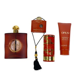 May include: A collection of Yves Saint Laurent Opium products. Includes a perfume bottle, a travel-sized perfume atomizer, a cylindrical perfume container, and a body moisturizer tube. All items are in shades of red and gold.