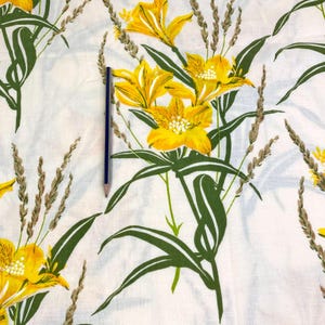 May include: White fabric with a yellow floral print. The flowers are stylized and have a yellow center with five petals. The leaves are green and the stems are brown.