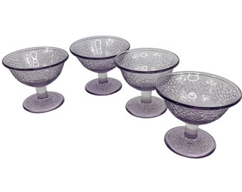 May include: Four clear glass dessert dishes with a textured, frosted, purple finish. The dishes have a pedestal base.