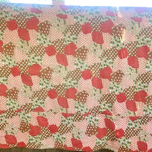 Puede incluir: Una colcha de retazos con un patrón geométrico en tonos de rosa, rojo y verde. La colcha está hecha de diferentes telas con estampados florales.