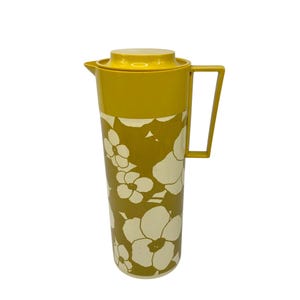 Puede incluir: Jarra amarilla mostaza vintage con tapa y asa a juego. La jarra presenta un estampado floral en crema y verde oliva. La jarra mide aproximadamente 30 cm de altura.