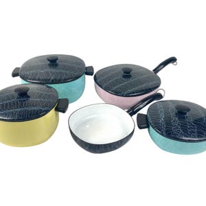 May include: A collection of colorful enamel cookware. The set includes pots and pans in pastel shades of yellow, pink, and blue, each with a black lid featuring a white swirl pattern. One pan has a handle.