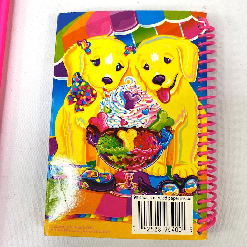 May include: A spiral-bound notebook with a colorful cover featuring two yellow cartoon puppies. The puppies are next to a large ice cream sundae. The notebook has a pink spiral binding and the text "90 sheets of ruled paper inside".