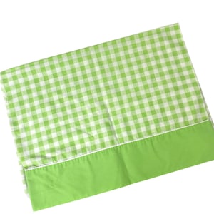 May include: A green and white gingham patterned sheet with a solid green border. The sheet is folded, showing the pattern and border. The sheet is made of a soft, likely cotton material.